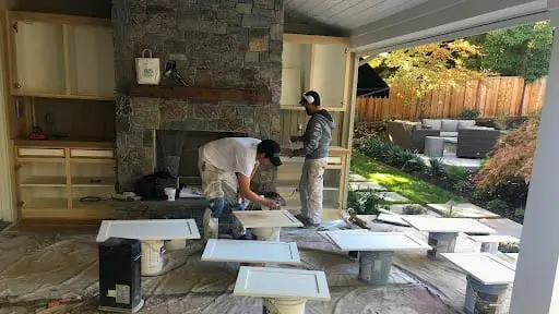 Painter refinishing cabinets in an outdoor kitchen